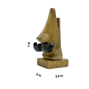 May include: Wooden phone stand shaped like a nose with a black mustache. The stand is 7 inches tall, 4 inches wide, and 2.5 inches deep.