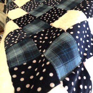 Könnte beinhalten: Eine Patchwork-Decke mit einem karierten Muster in Blautönen und Weiß. Die Decke ist aus verschiedenen Stoffen gefertigt, darunter karierter Stoff und Punkte.