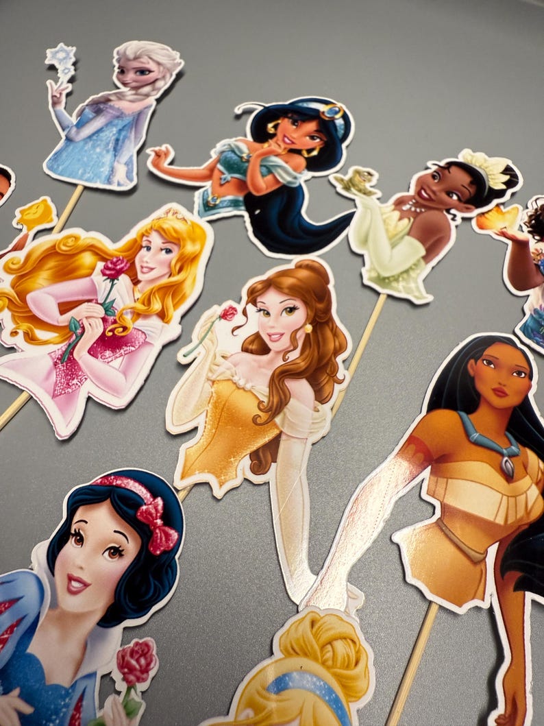May include: A set of 8 princess character cake toppers. The toppers are printed on cardstock and feature Disney princesses such as Snow White, Belle, Jasmine, Pocahontas, and more. Each topper has a wooden stick attached to the back.