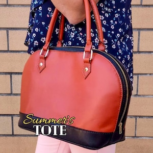 May include: A two-tone tote bag with a rounded shape. The top portion is a reddish-brown color, and the bottom is black. The bag has a zipper closure and two handles. The text "Summer's TOTE" is printed on the bottom of the bag.