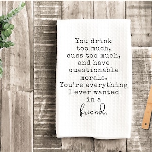 May include: A white kitchen towel with the text "You drink too much, cuss too much, and have questionable morals. You're everything I ever wanted in a friend." A wooden spoon and a potted plant are also visible.