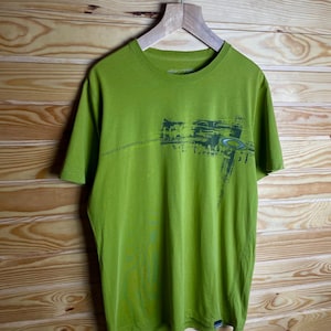 May include: A green t-shirt with a graphic print of a city skyline and the text "DARK SKY" on the front. The shirt has a crew neck and short sleeves.