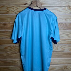 K&ouml;nnte beinhalten: Ein hellblaues T-Shirt mit kurzen &Auml;rmeln und dunkelblauem Besatz an Kragen und &Auml;rmeln.