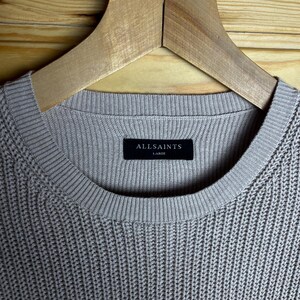 May include: A light gray ribbed knit sweater with a black tag that reads "ALLSAINTS" and "LARGE".