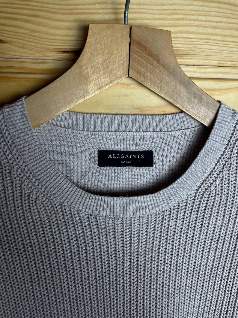May include: A light gray ribbed knit sweater with a black tag that reads "ALLSAINTS" and "LARGE".