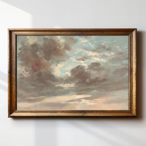 May include: A framed landscape painting of a cloudy sky. The artwork features a palette of muted colors, including shades of gray, blue, and pink. The wooden frame adds a classic touch to the artwork, suitable for home decor.