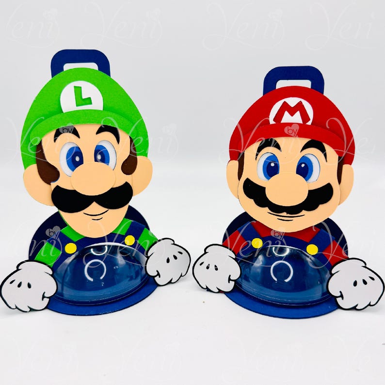 Puede incluir: Dos recipientes con forma de personajes, uno verde y otro rojo, que se asemejan a Luigi y Mario de la franquicia Super Mario Bros. Cada uno tiene una base azul, manos blancas y un asa. El recipiente de Luigi tiene un sombrero verde con una "L" blanca, y el recipiente de Mario tiene un sombrero rojo con una "M" blanca.