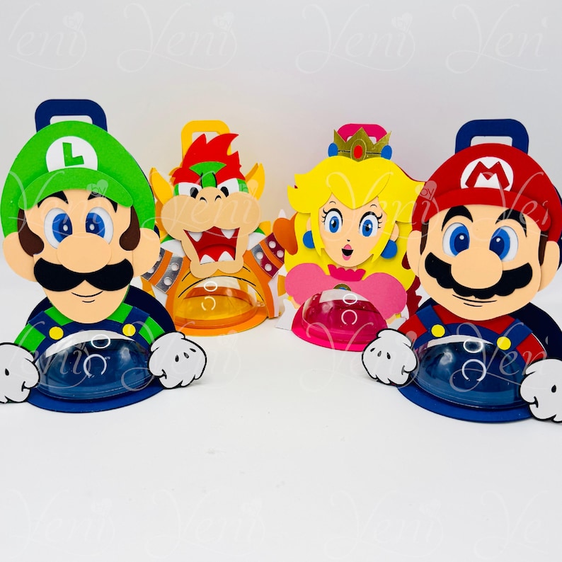 Puede incluir: Cuatro recipientes coloridos con forma de personajes, con Mario, Luigi, Bowser y la Princesa Peach. Cada recipiente tiene una base transparente y redondeada y un dise&ntilde;o espec&iacute;fico del personaje, con un asa en la parte superior.