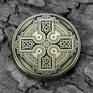 Peut inclure: Un motif celtique en forme de nœud rond en métal doré sur fond noir. Le motif représente une croix avec quatre nœuds sur chaque bras et un cercle autour de l'extérieur.
