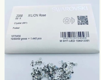 May include: A small white package with the text "SWAROVSKI" and "XILION Rose" printed on it. The package contains 1,440 clear, faceted rhinestones. The package also includes a barcode and a QR code.
