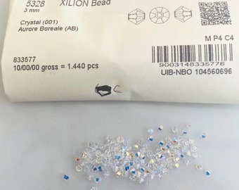May include: A package of XILION beads, 3 mm in size, with the text "Crystal (001) Aurore Boreale (AB)". The beads are clear with an iridescent finish. The package also includes the text "5328", "833577", and a barcode.