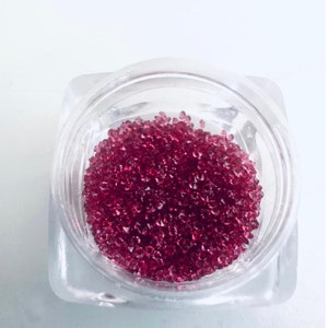 May include: A small clear container filled with tiny pink iridescent rhinestones.