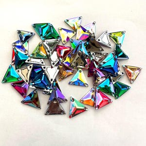May include: Assortment of iridescent triangle-shaped rhinestones in various colours, including green, blue, red, and purple.