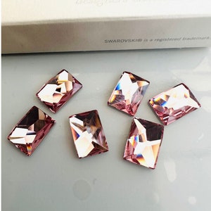 May include: Six pink rectangular crystal rhinestones. The rhinestones have a faceted design and a clear, iridescent finish.