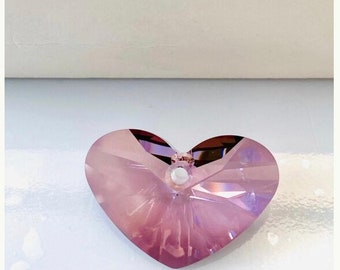 May include: A pink crystal heart charm with a hole for stringing. The charm is made by Swarovski.