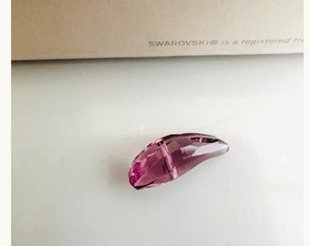 May include: A single, pink crystal bead with a hole in the center. The bead is shaped like a teardrop and has a glossy finish.