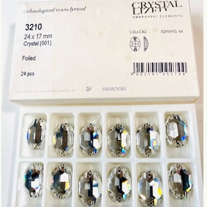 May include: A box containing 24 clear crystal rhinestones, each measuring 24 x 17 mm. The rhinestones are arranged in two rows of 12, and the box is labelled with the product number 3210, the size, and the brand name Swarovski.