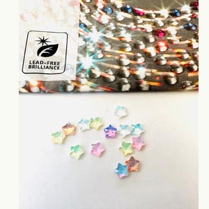 May include: Assortment of pastel-colored star-shaped rhinestones. The rhinestones are iridescent and have a clear, glassy finish.