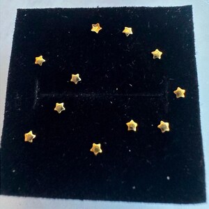 Op de afbeelding: Een zwarte fluwelen display case met tien gouden stervormige studs.