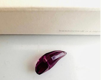May include: A deep purple crystal teardrop pendant, with a faceted design, is shown on a white surface.