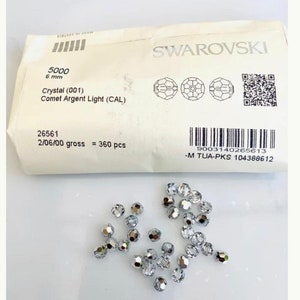 May include: A packet of 360 silver-coloured 6 mm crystal beads from Swarovski. The packet label reads "5000 Crystal (001) Comet Argent Light (CAL)" and "26561 2/06/00 gross = 360 pcs".