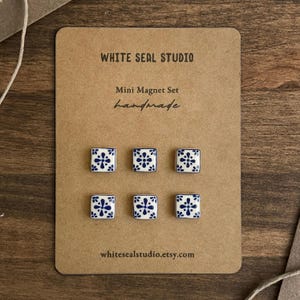 Puede incluir: Un juego de seis imanes cuadrados sobre una tarjeta rectangular marrón etiquetada WHITE SEAL STUDIO Mini Magnet Set handmade. Cada imán presenta una base blanca con un patrón floral azul. La tarjeta incluye el texto whitesealstudio.etsy.com.