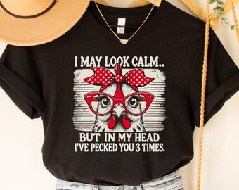 May include: Black t-shirt with a graphic of a chicken wearing glasses and a red bow. The text on the shirt reads "I may look calm... but in my head I've pecked you 3 times."