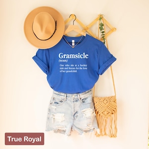 May include: A royal blue t-shirt with a white graphic that says "Gramsicle (noun) One who sits at a hockey rink and freezes for the love of her grandchild."