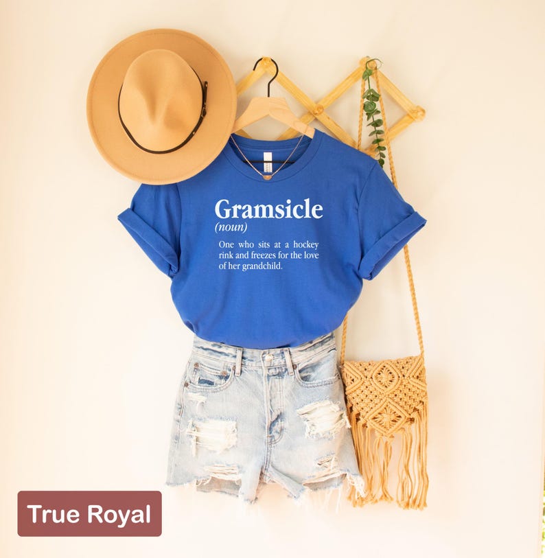 May include: A royal blue t-shirt with a white graphic that says "Gramsicle (noun) One who sits at a hockey rink and freezes for the love of her grandchild."