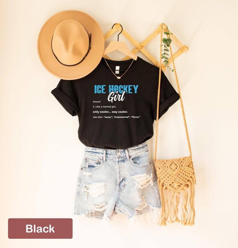 Op de afbeelding: Zwart T-shirt met de tekst "ICE HOCKEY Girl" en een definitie van het woord "Girl" als "Net als een normaal meisje, alleen cooler... veel cooler."