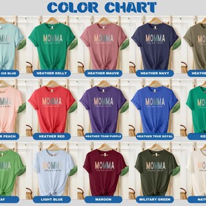 May include: Color chart showing 15 different t-shirt colors. Each t-shirt has the word "MOMMA" printed on it in a rainbow gradient.