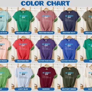 Op de afbeelding: Kleurenkaart met 15 verschillende T-shirt kleuren. Elk T-shirt heeft een ontwerp met de tekst "ICE HOCKEY Girl" met een definitie van de term. De kleuren omvatten Heather Ice Blue, Heather Kelly, Heather Mauve, Heather Navy, Heather Olive, Heather Peach, Heather Red, Heather Team Purple, Heather True Royal, Kelly, Leaf, Light Blue, Maroon, Military Green en Natural.