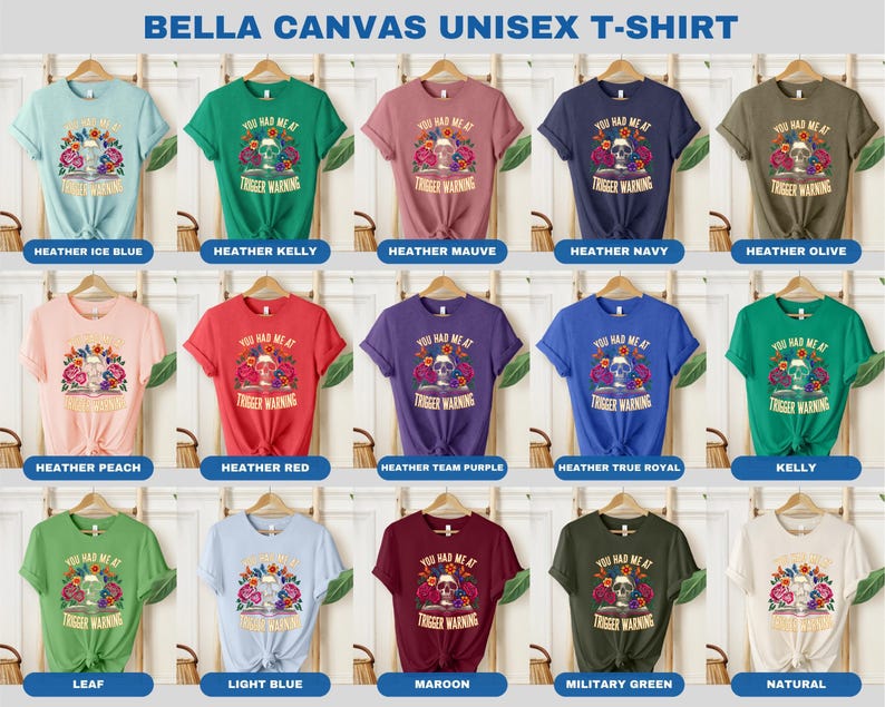 Puede incluir: Una camiseta unisex Bella Canvas con una calavera con flores y el texto "You Had Me At Trigger Warning". La camiseta est&aacute; disponible en 15 colores diferentes, incluyendo azul hielo jaspeado, kelly jaspeado, malva jaspeado, azul marino jaspeado, oliva jaspeado, melocot&oacute;n jaspeado, rojo jaspeado, morado jaspeado, azul real jaspeado, kelly, hoja, azul claro, granate, verde militar y natural.