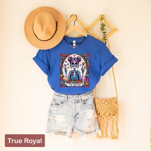 May include: A blue t-shirt featuring a colourful illustration of a skeleton holding paintbrushes and a palette. The text "The Crafter" is below the image.