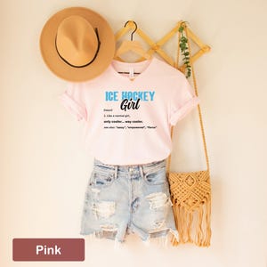 Op de afbeelding: Roze T-shirt met de tekst "ICE HOCKEY Girl (zelfstandig naamwoord) 1. Net als een normaal meisje, alleen cooler... veel cooler. zie ook: "sassy", "empowered", "fierce" "