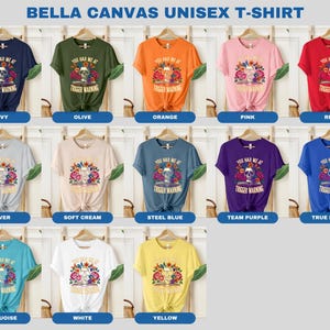 Puede incluir: Una camiseta unisex Bella Canvas con una calavera con flores y el texto "You had me at trigger warning". La camiseta est&aacute; disponible en 12 colores: azul marino, oliva, naranja, rosa, rojo, plata, crema suave, azul acero, morado equipo, azul real, turquesa, blanco y amarillo.