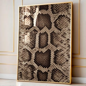 Könnte beinhalten: Gerahmtes Kunstwerk mit einem detaillierten Schlangenhautmuster in Braun-, Beige- und Grautönen. Das rechteckige Kunstwerk ist in einem goldfarbenen Rahmen eingefasst. Das Schlangenhautdesign ist eine detaillierte Nahaufnahme, die eine strukturierte Optik bietet.