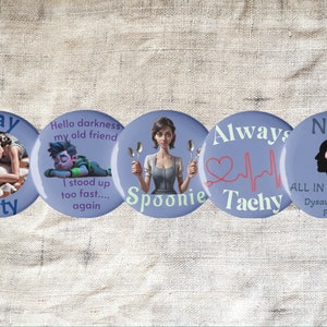Pode incluir: Quatro botões redondos azuis com texto branco e imagens. Os botões dizem "Stay Salty", "Hello darkness my old friend I stood up too fast... again", "Always Tachy", e "NOT ALL IN MY HEAD Dysautonomia POTS".