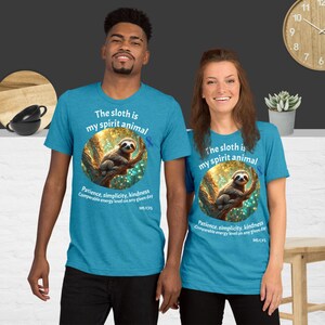 May include: Two turquoise blue t-shirts with a sloth graphic and the text "The sloth is my spirit animal". The graphic features a sloth on a tree branch with a golden glow. The text "Patience, simplicity, kindness. Comparable energy level on any given day. ME/CFS" is below the graphic.