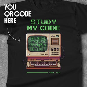 Puede incluir: Una camiseta negra con un diseño de computadora retro. La computadora tiene una pantalla verde con un código QR y el texto "STUDY MY CODE". El texto "YOU QR CODE HERE" está en la esquina superior izquierda de la camiseta. El texto "ESTD. 1973" está en la parte inferior de la computadora.