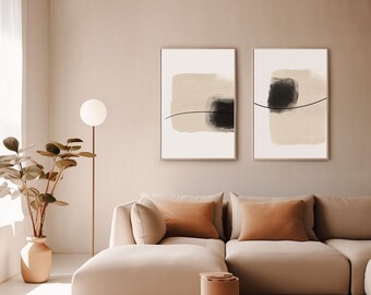 May include: Two abstract art prints with black and beige shapes on a white background. The prints are framed and hanging on a beige wall above a beige sectional sofa.