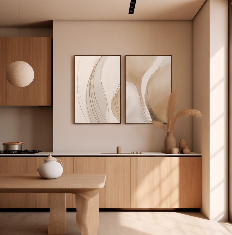 May include: A modern kitchen with light wood cabinetry and a matching wooden table. Two framed abstract art pieces hang on the wall. A white teapot sits on the table. A decorative light fixture hangs from the ceiling.