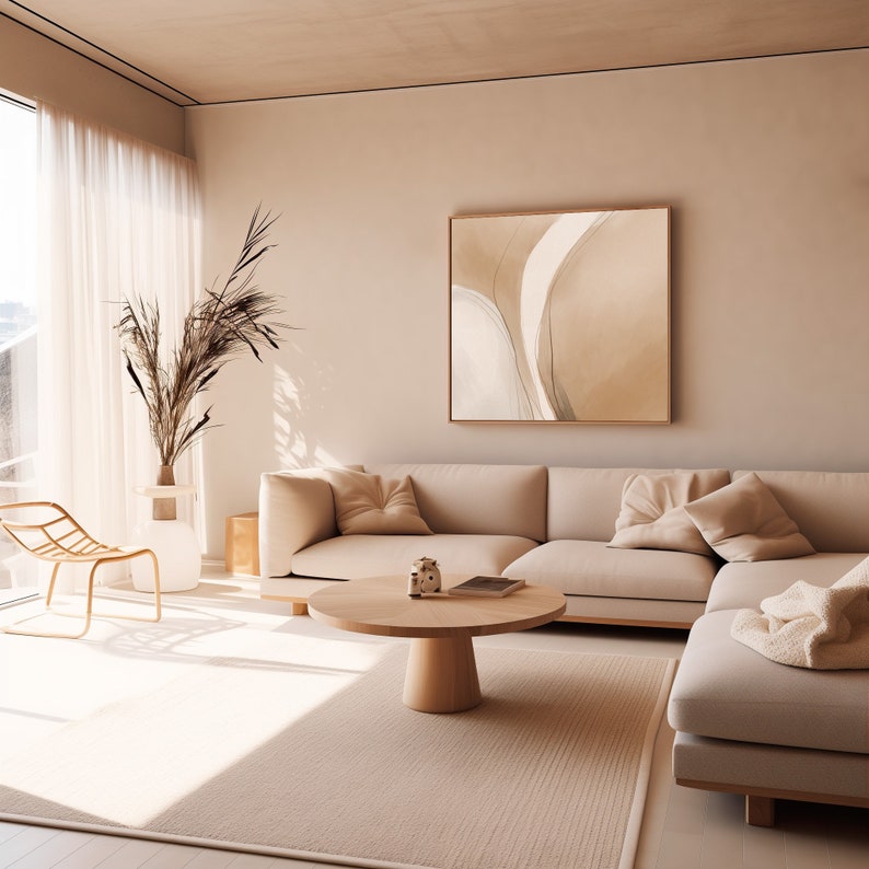 May include: A modern living room with a neutral color palette. A large beige sectional sofa with throw pillows sits on a light-colored rug. A round wooden coffee table and a framed abstract artwork complete the space. A decorative vase with dried plants and a gold chair are also present.