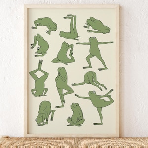 Könnte beinhalten: Ein gerahmter Druck mit grünen Frosch-Illustrationen in verschiedenen Yoga-Posen. Das Kunstwerk hat einen hellbeigen Hintergrund und einen Naturholzrahmen. Der Druck wird auf einer gewebten Bank mit dekorativen Laternen präsentiert.