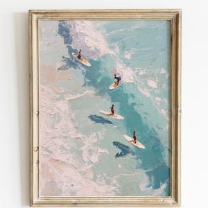Puede incluir: Impresión artística enmarcada que presenta una pintura de acuarela de surfistas sobre olas. La obra representa a varios surfistas en tablas de surf en un océano turquesa con olas blancas y espumosas. El marco es de color marrón claro.