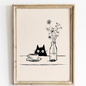 Puede incluir: Impresión artística enmarcada con una ilustración en blanco y negro. Representa un gato negro mirando por encima de una mesa, una taza y un platillo, y un jarrón con flores. El fondo es de color beige neutro.