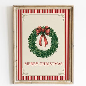 Puede incluir: Impresión navideña enmarcada con una corona verde y un lazo rojo. La impresión tiene un fondo crema con rayas verticales rojas y las palabras "MERRY CHRISTMAS" en rojo, dentro de un marco de madera.