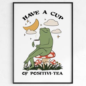 Puede incluir: Una rana verde sentada en un hongo rojo y blanco, sosteniendo una taza de té. El texto "HAVE A CUP OF POSITIVI-TEA" está escrito debajo de la rana.