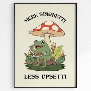 Puede incluir: Una impresión artística enmarcada con una ilustración caprichosa. Una rana verde come espaguetis bajo una seta. El texto dice "MORE SPAGHETTI" arriba y "LESS UPSETTI" abajo. Fondo crema.