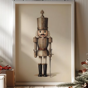 Puede incluir: Una figura de cascanueces de estilo vintage en un marco blanco. El cascanueces lleva un uniforme marrón y dorado con un sombrero negro y sostiene una espada. El fondo es de color beige claro.